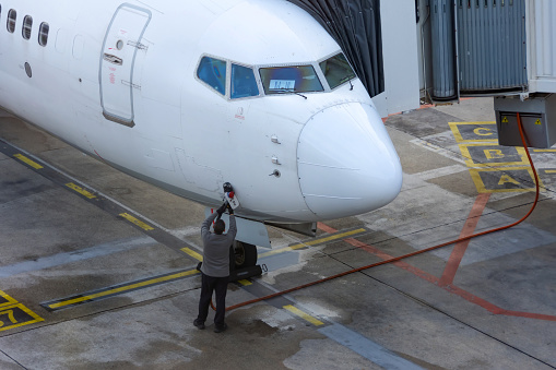 Airliner Cockpit, Ground power unit is still pluged in and providing electricity on board. The service technician connects the power cable to the fixed ground power supply