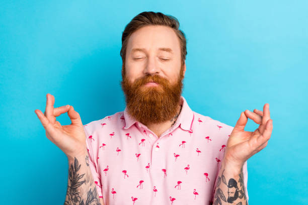 Portrait of positive carefree person closed eyes hands fingers meditate retreat isolated on blue color background Portrait of positive carefree person closed eyes hands fingers meditate retreat isolated on blue color background. man yoga tattoo stock pictures, royalty-free photos & images
