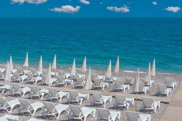istock Landscape coastline with white beach umbrellas and deck chairs on a sandy beach, against the backdrop of the sea horizon. 1633483705