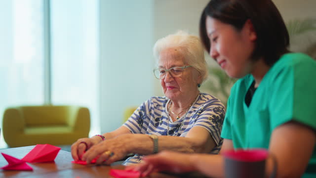 Senior woman learning making origami as for physiotherapy activity