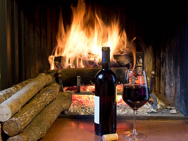 Glass of wine next to a fireplace stock photo