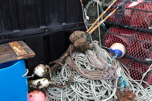 St Abbs, Berwickshire, Scotland, Uk. 28th March 2023. Tools of the lobster fishing trade with lobster pots, floats, marker flags, plastic floats and a blue plastic bin.