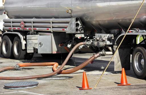 Fuel tanker deposits gasoline into storage tank at the gas station.