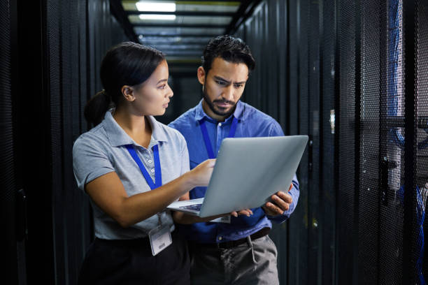 Laptop, server room and technician people problem solving in database management, system upgrade or cyber security. Error, data center or engineer employees, information technology and programming stock photo