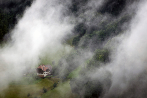 black forest farm house behind fog