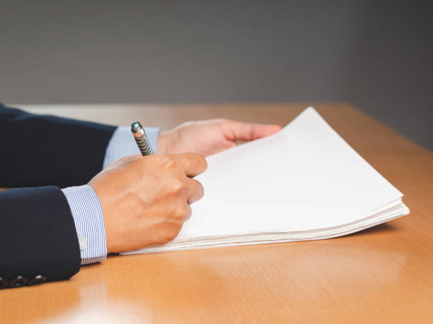 istock Close-up of a businessman signing on documents while sitting working in the office 1633509520