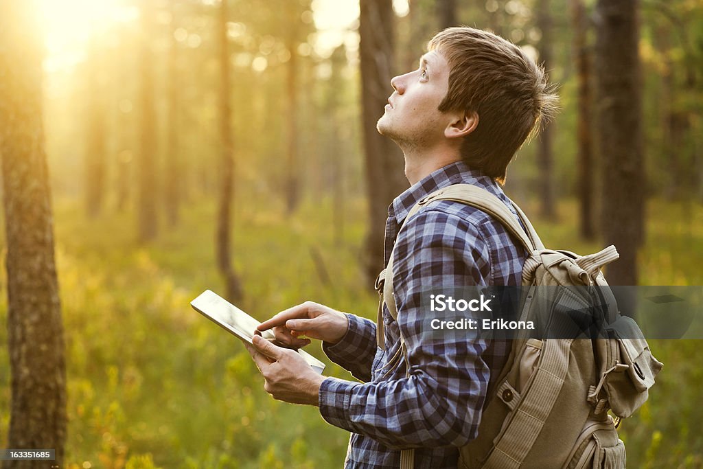 Man using digital tablet in the nature in a sunny day Man Using Digital Tablet in Forest Adult Stock Photo