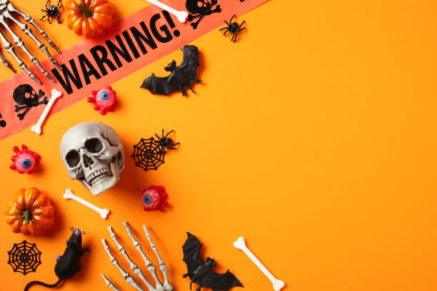 istock Happy Halloween holiday concept. Flat lay composition with skull, bats, spiders, warning tape, pumpkins, skeleton hands on orange background. 1633553977