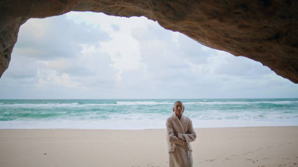 istock Peaceful traveler explore seashore walking beach. Curly woman hiding ocean cave 1633557753