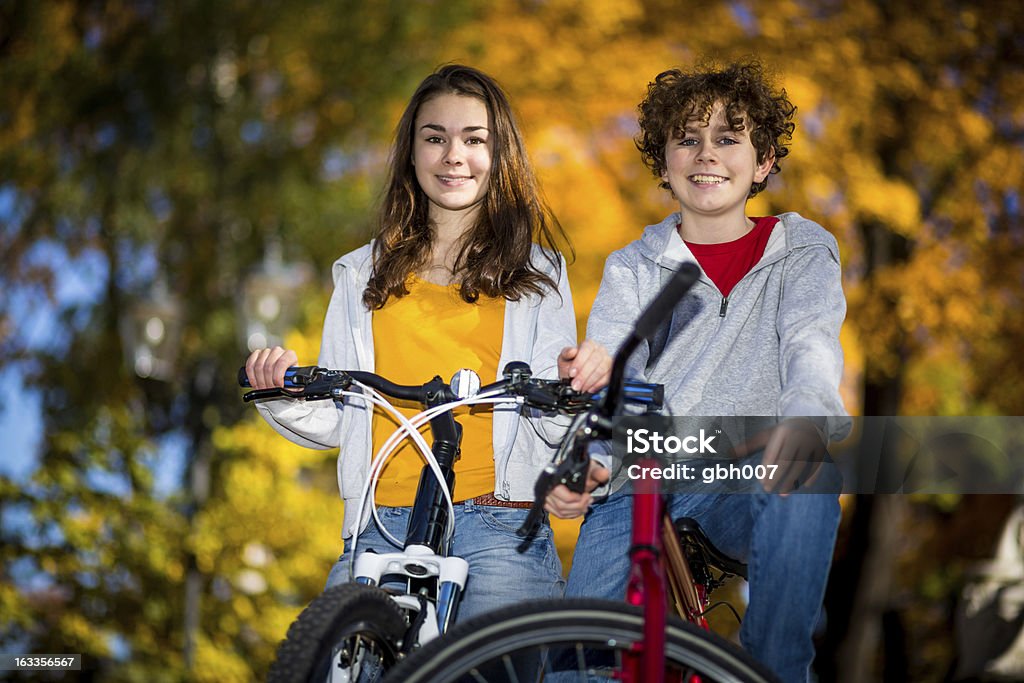 Urban biking- Menina e menino andando de bicicleta no parque da cidade - Foto de stock de 14-15 Anos royalty-free