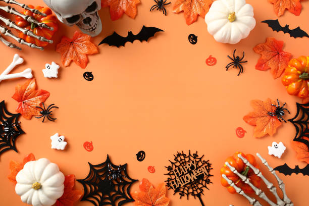 istock Happy Halloween flat lay composition with spooky skull, bats, spiders, webs, pumpkins, skeleton hands on orange background. 1633565911