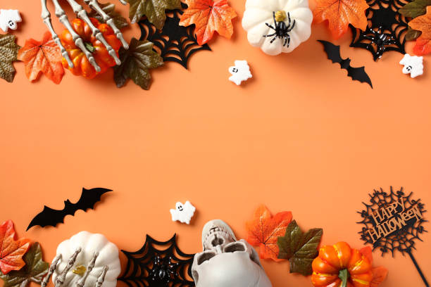 istock Happy Halloween banner design. Flat lay pumpkins, spiders, webs, skeleton hands, ghosts on orange background. 1633571875