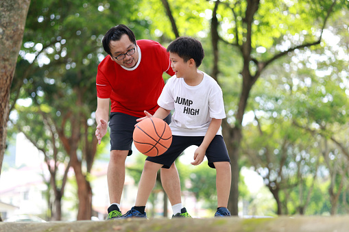 Father and son playing basketball in a Public Park