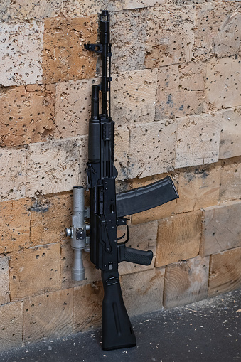 Rifle with old-fashion optical sight staying by the wall in a shooting range, close up photo