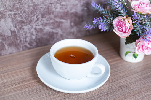 A cup of Chinese tea on wooden table. Beverage for healthy with rose flower in pot