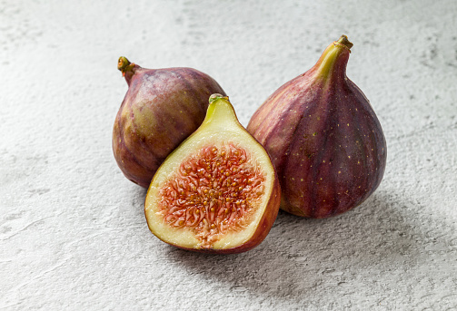 View of whole and cut organic figs on stone table