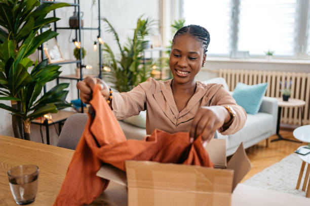 istock Young Woman Unboxing A Package With A New Shirt She Ordered Online 1633620028