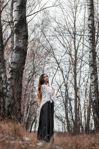 Autumn Enchantment: Girl in a Long Black Dress with Scarf and Flowing Hair in the Woods