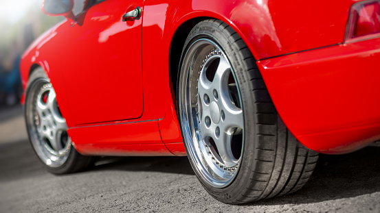 Details of rim and new tire of a red vintage car, selective focus on the rim