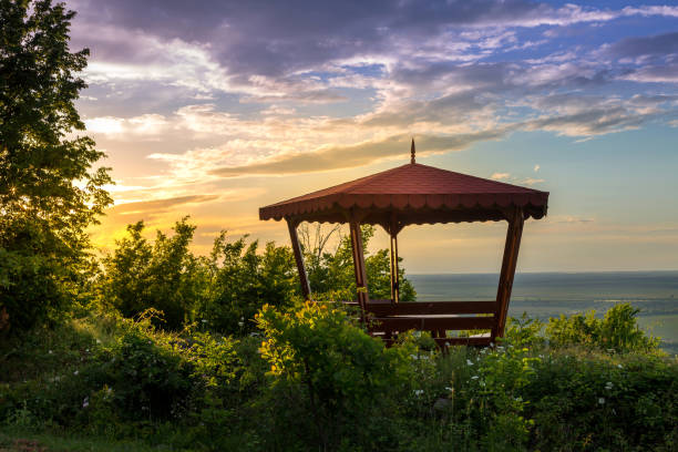 Wooden gazebo over summer sunset landscape