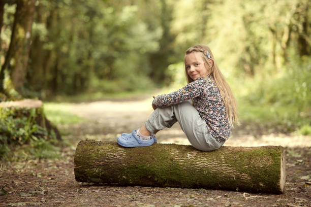 통나무에 앉아 있는 여덟 살 소녀 스톡 사진
