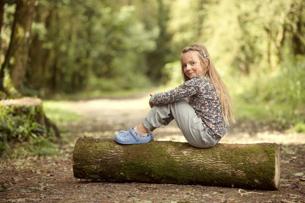 Eight-year-old girl sitting on a log - fotografia de stock