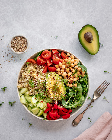 Overhead view of a colorful salad bowl filled with quinoa, chickpeas, avocado and veggies