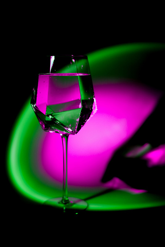 transparent glass of irregular angular shape with bright blurry uneven spots of bright neon color.texture.background