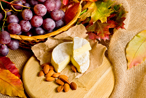 Grapes with cheese and almonds on background of a burlap and autumn leaves