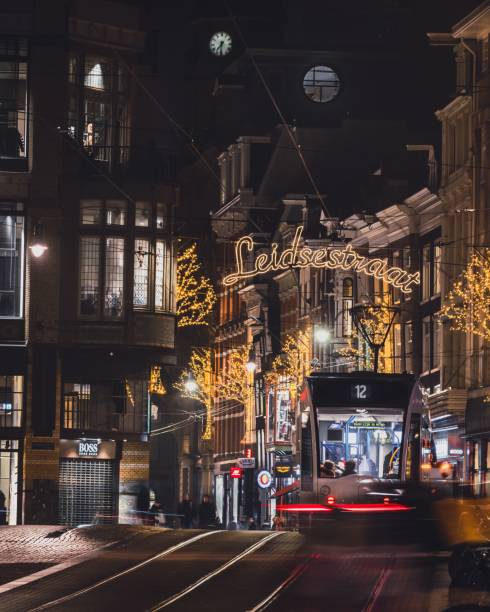 Amsterdam, Netherlands – November 28, 2022: A tram passing along Leidestraat at night, under Christmas lights in Amsterdam, Netherlands