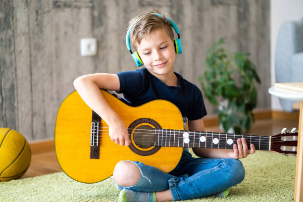 istock Boy playing acoustic guitar at home 1633718444