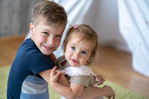 adorable redhead siblings hugging and smiling at camera isolated on white