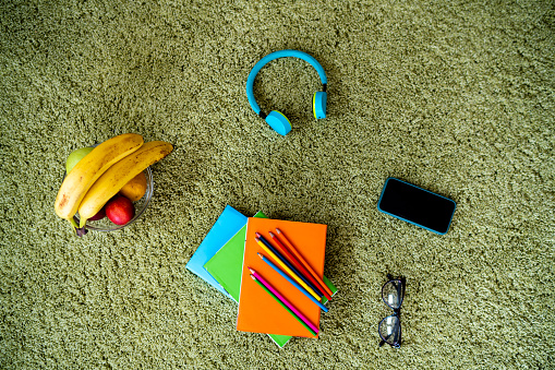 High angle view of school supplies and fruit at the carpet