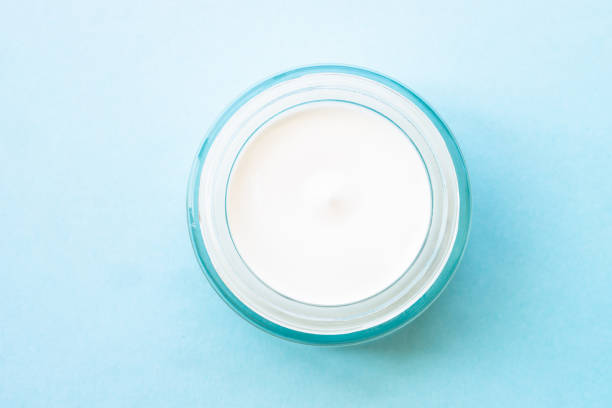 istock Natural cosmetic, cream jar with green leaves on blue. 1633764344