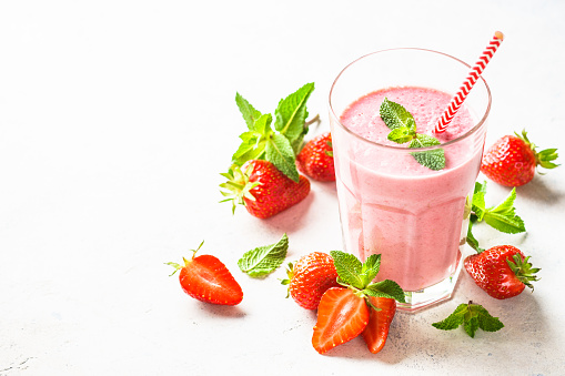 Strawberry smoothie or milkshake at white table.