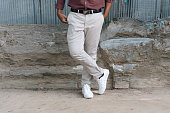 Man standing on the floor with cream pants and white canvas shoes.