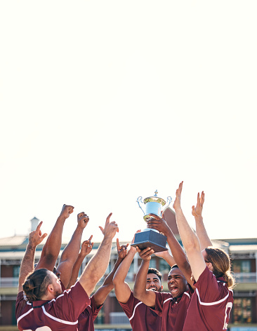 Rugby, team and winning with trophy, champion and men at stadium with success, celebration and achievement. Male people outdoor, exercise and competition, sports game and cheers with mockup space