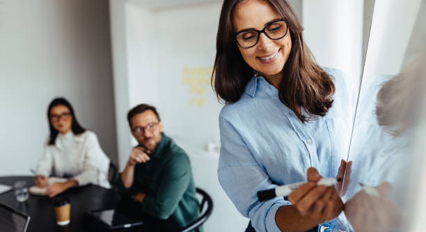 istock Business woman writing on a board during a presentation 1633791856