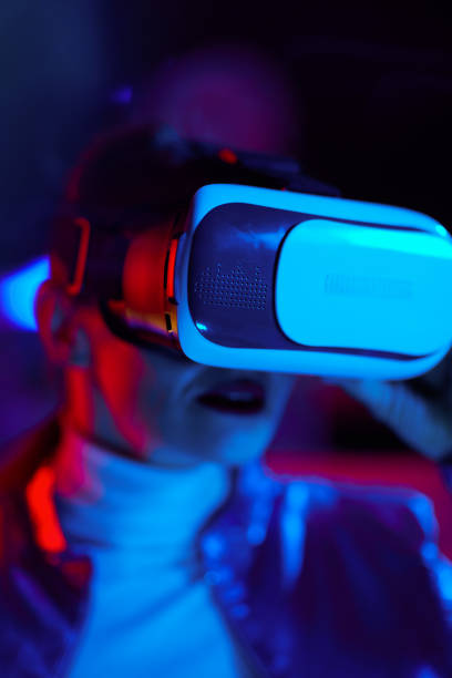 istock Trendy woman in virtual reality goggles on dark 1633802569