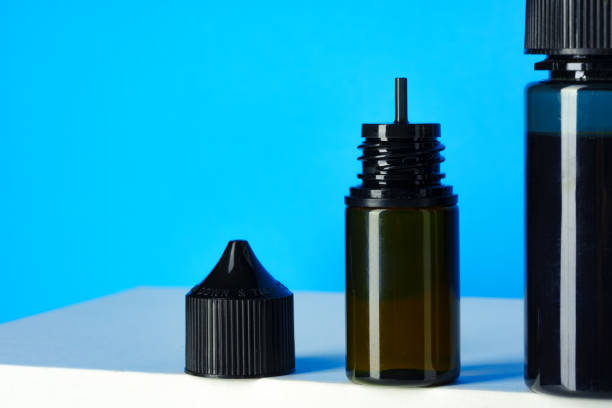 istock Black electronic cigarettes liquid bottles on blue background 1633817542