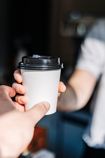 Close up woman hands gives paper coffee cup