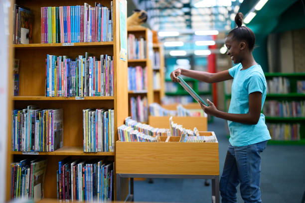istock Smiling girl holding & looking at a library storybook 1633829070