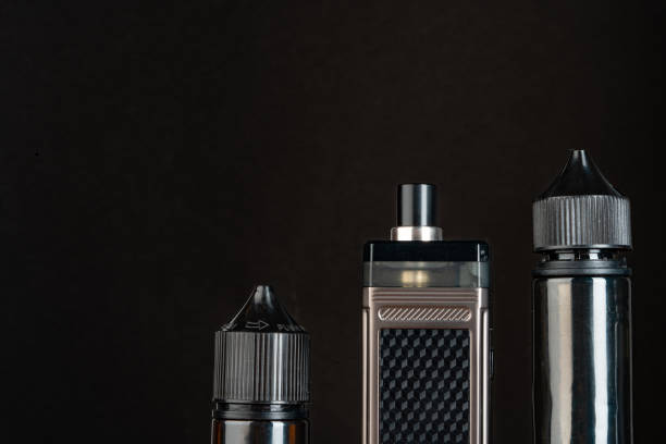 istock Vape and vape liquid bottles against black background 1633835345