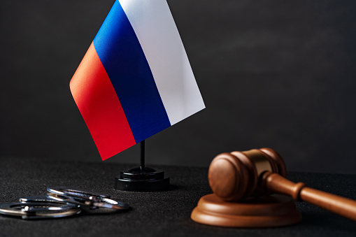 Russia flag with judge mallet and handcuffs on black background close up