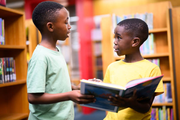istock Excited young boys discussing a storybook in the library 1633845580