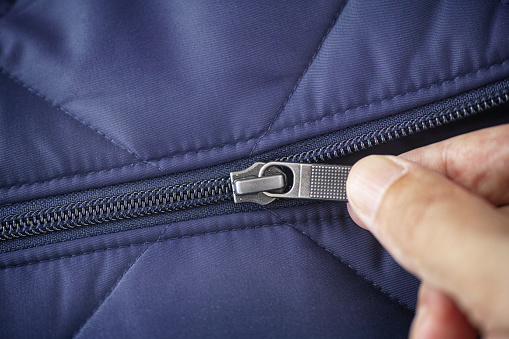 Closeup shot of a zipper on a blue jacket. Unzip a zip. Close up.