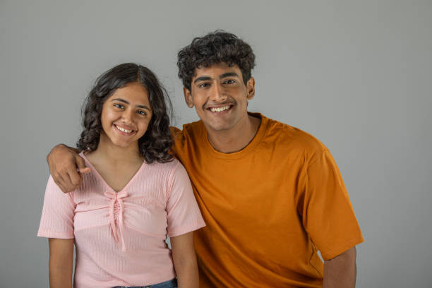 istock Happy teenage siblings standing over white background 1633870082