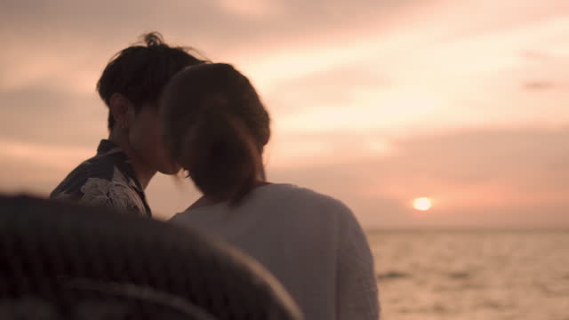 Couple in love watching the enjoying beautiful sunset sea view on a van.