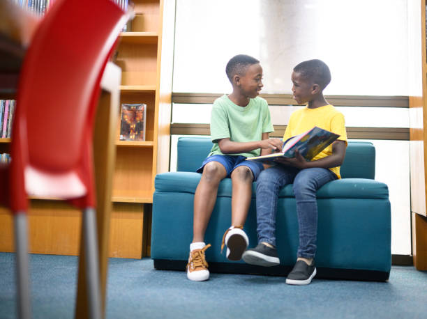 istock Full length front view friends reading storybook together 1633873642