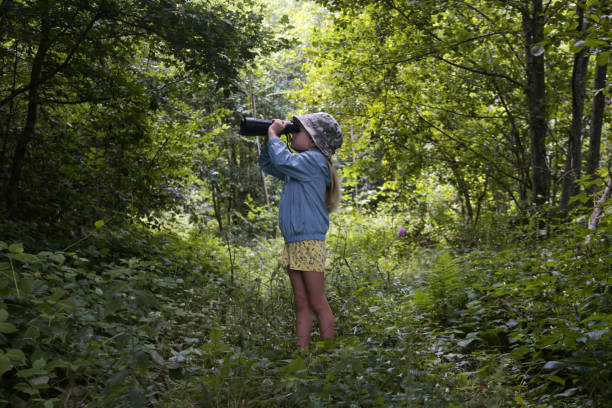 istock Cute little girl exploring nature looking through binoculars. Child playing outdoors. Kids travel, adventure and bird watching concept. 1633883330
